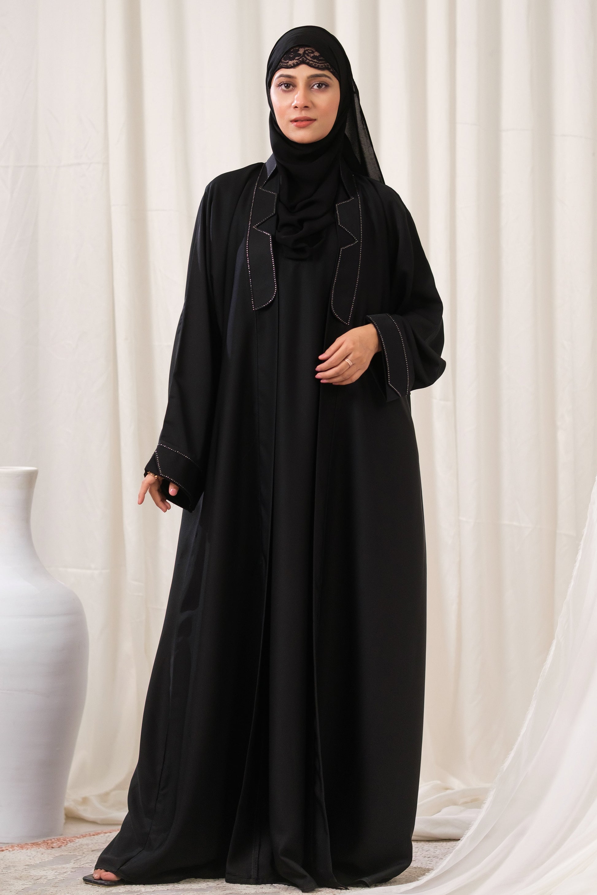 Dhaagey Apex Edge Front-Open Black Abaya in Nidha, featuring a tailored lapel collar and subtle dark beadwork tracing the edges.