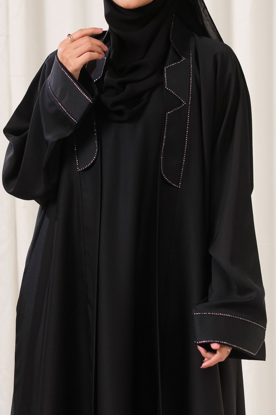 Dhaagey Apex Edge Front-Open Black Abaya in Nidha, featuring a tailored lapel collar and subtle dark beadwork tracing the edges.