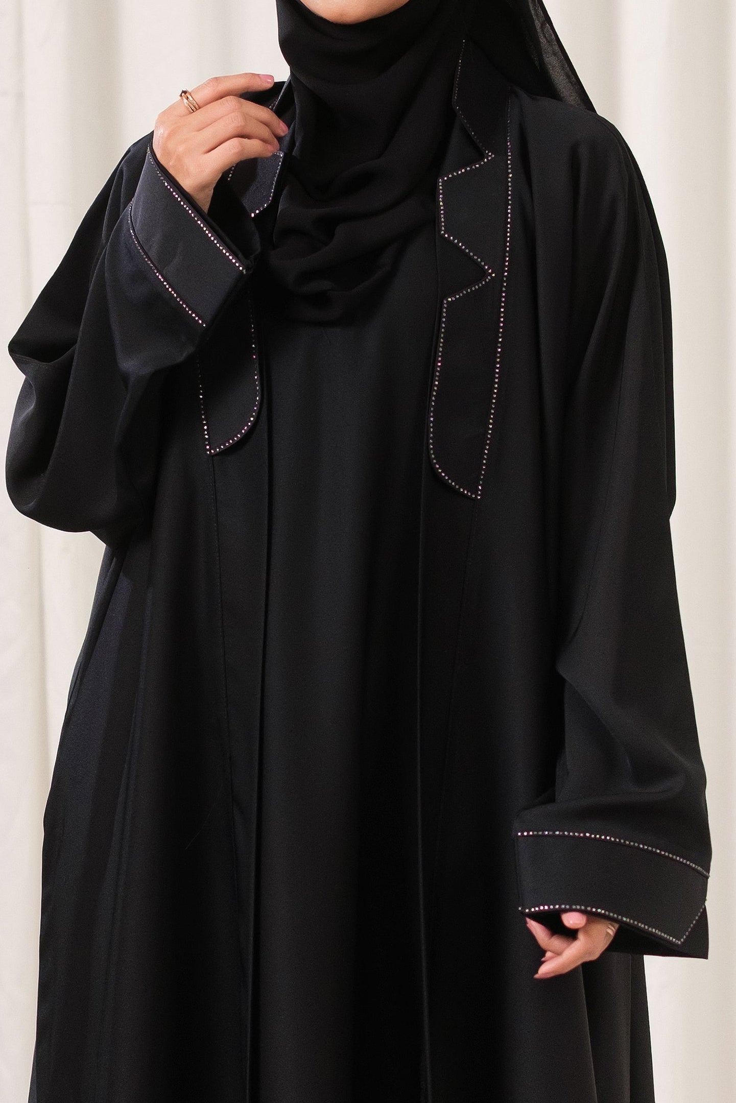 Dhaagey Apex Edge Front-Open Black Abaya in Nidha, featuring a tailored lapel collar and subtle dark crystals tracing the edges.
