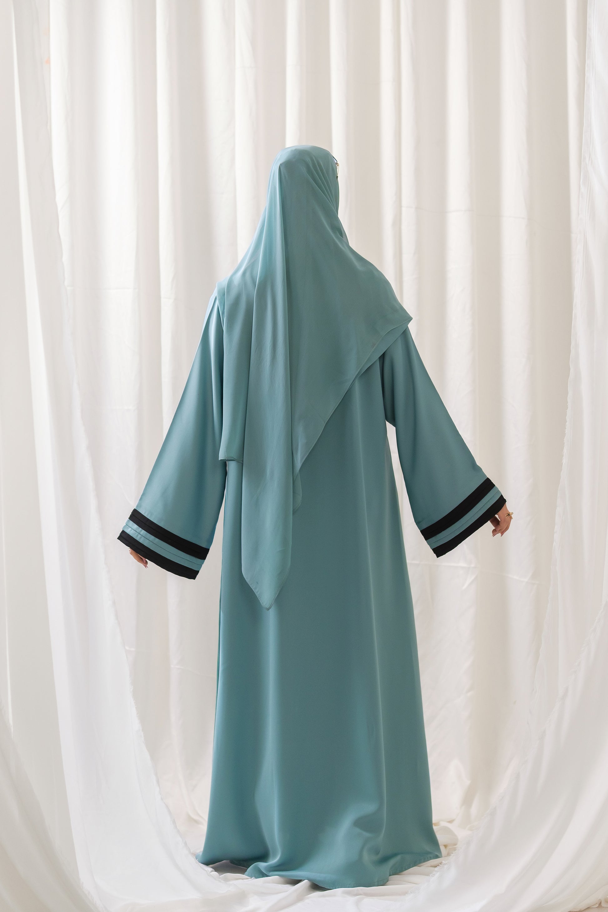 Dhaagey Aqua Serene Abaya in Imported Nidha Fabric with Black Contrast Trim, back view.