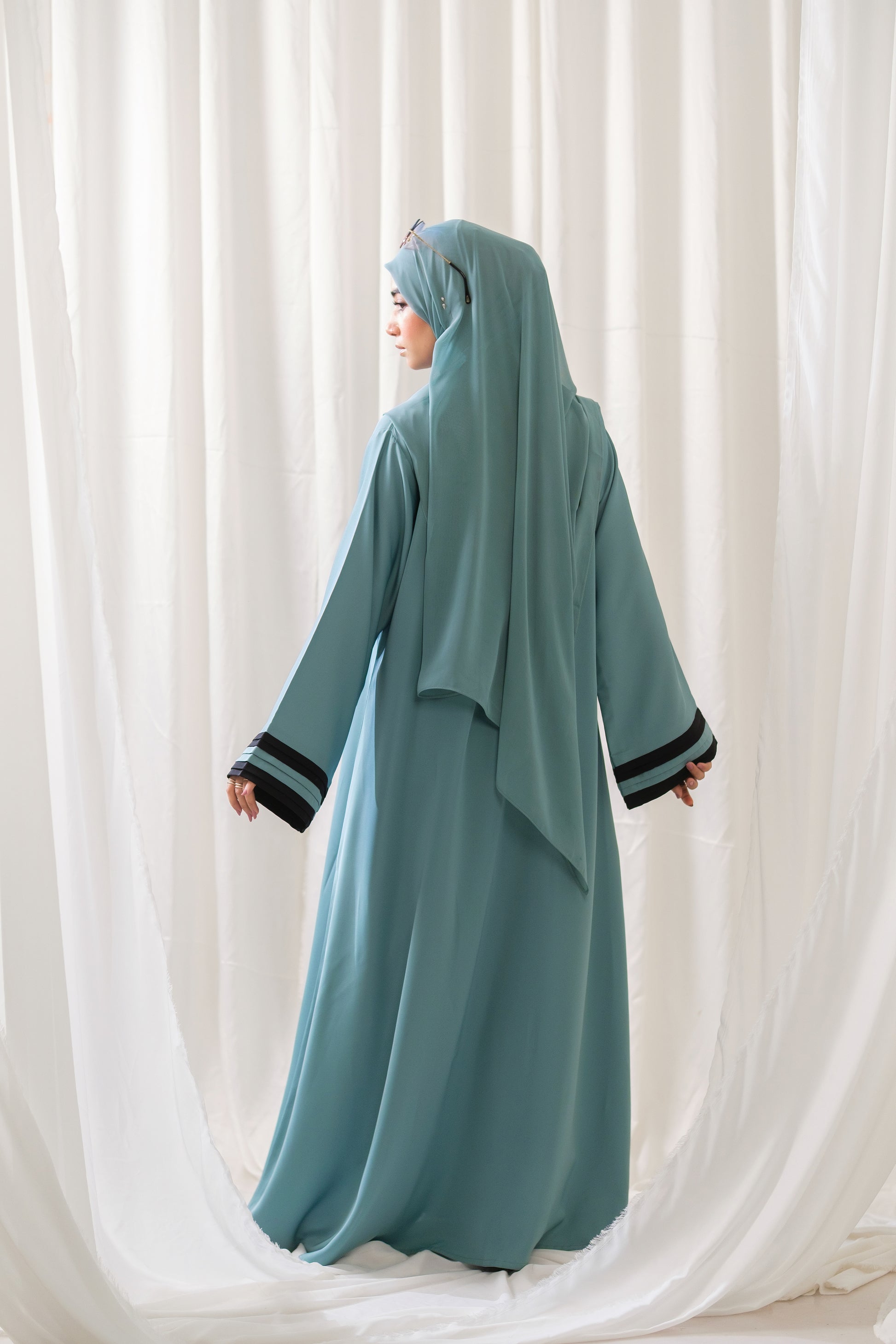 Dhaagey Aqua Serene Abaya in Imported Nidha Fabric with Black Contrast Trim, back side view.
