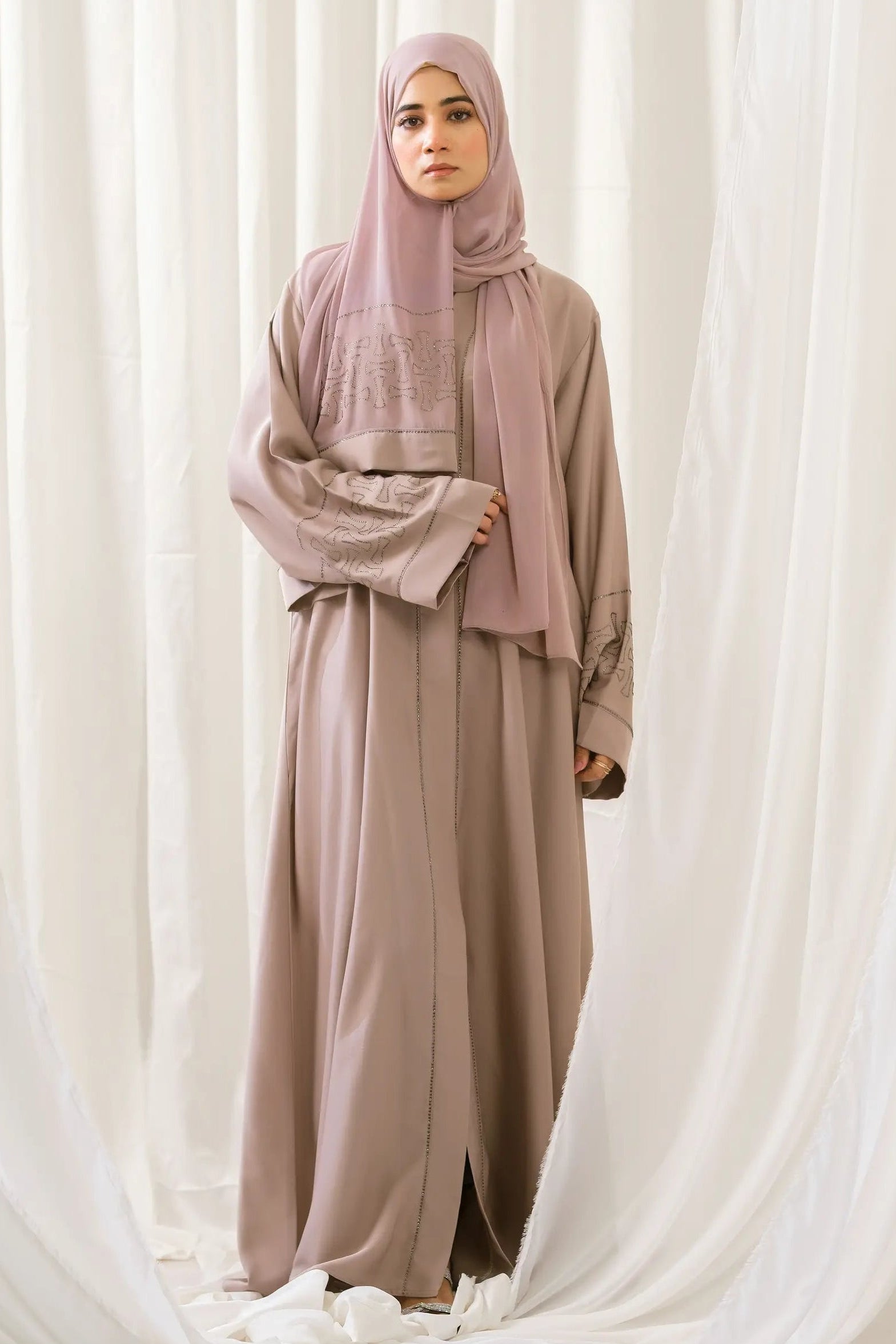 Full front view of the Dhaagey Crystal Lattice Abaya in warm beige Imported Nidha. The front-open design features delicate crystal trim along the neckline edge, with wide, shimmering geometric crystal lattice bands clearly visible on the sleeves.