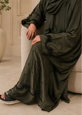 Detailed close-up of the Olive Arcana abaya hemline made of olive green imported Nidha fabric, highlighting intricate hand-beaded black glass scalloped archways accented with small scattered teardrop crystals against a marble floor