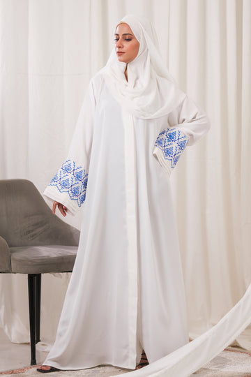 Dhaagey Isnik Motif White Front-Open Abaya in Nidha, showing the full flow and the bold Royal Blue embroidery on the wide cuffs.