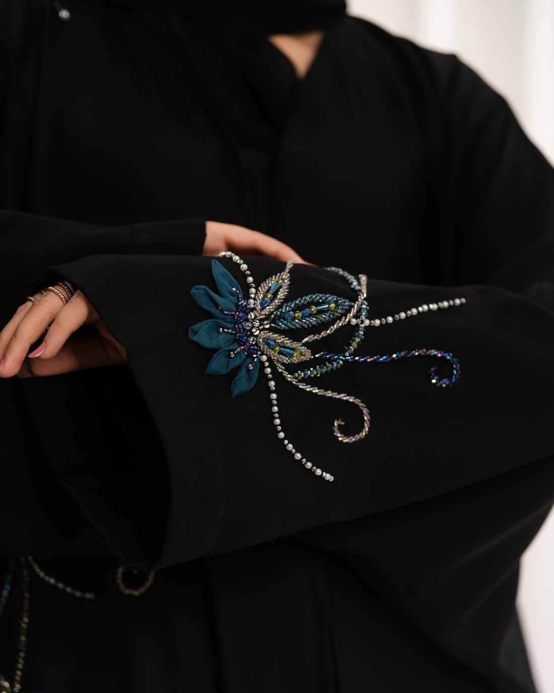 Dhaagey Lunar Whisper Abaya in deep black Nidha, full length, showing oversized front-open fit and luminous multi-toned beadwork flowing across the shoulder and cuff.