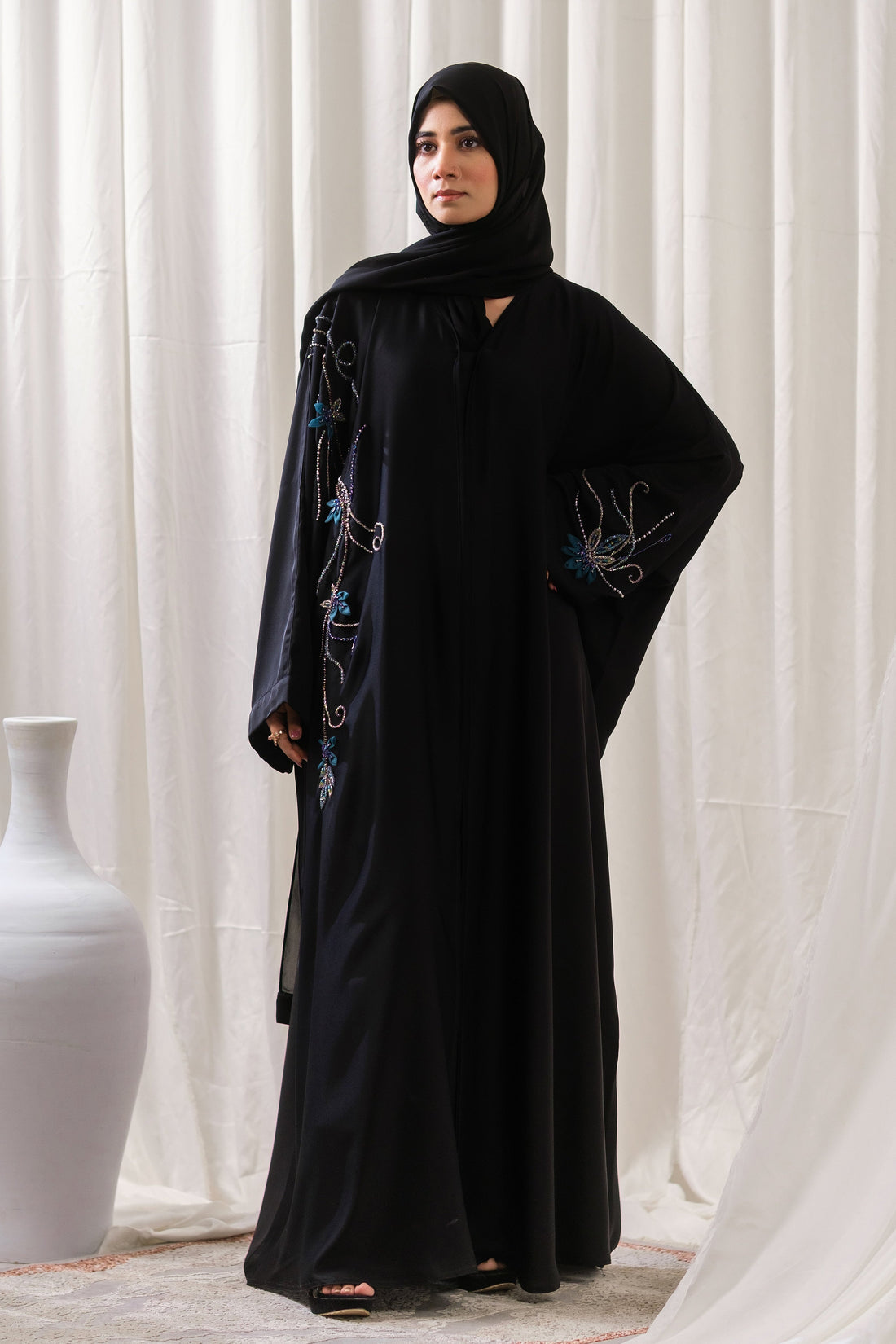 Dhaagey Lunar Whisper Abaya in deep black Nidha, full length, showing oversized front-open fit and luminous multi-toned beadwork flowing across the shoulder and cuff.