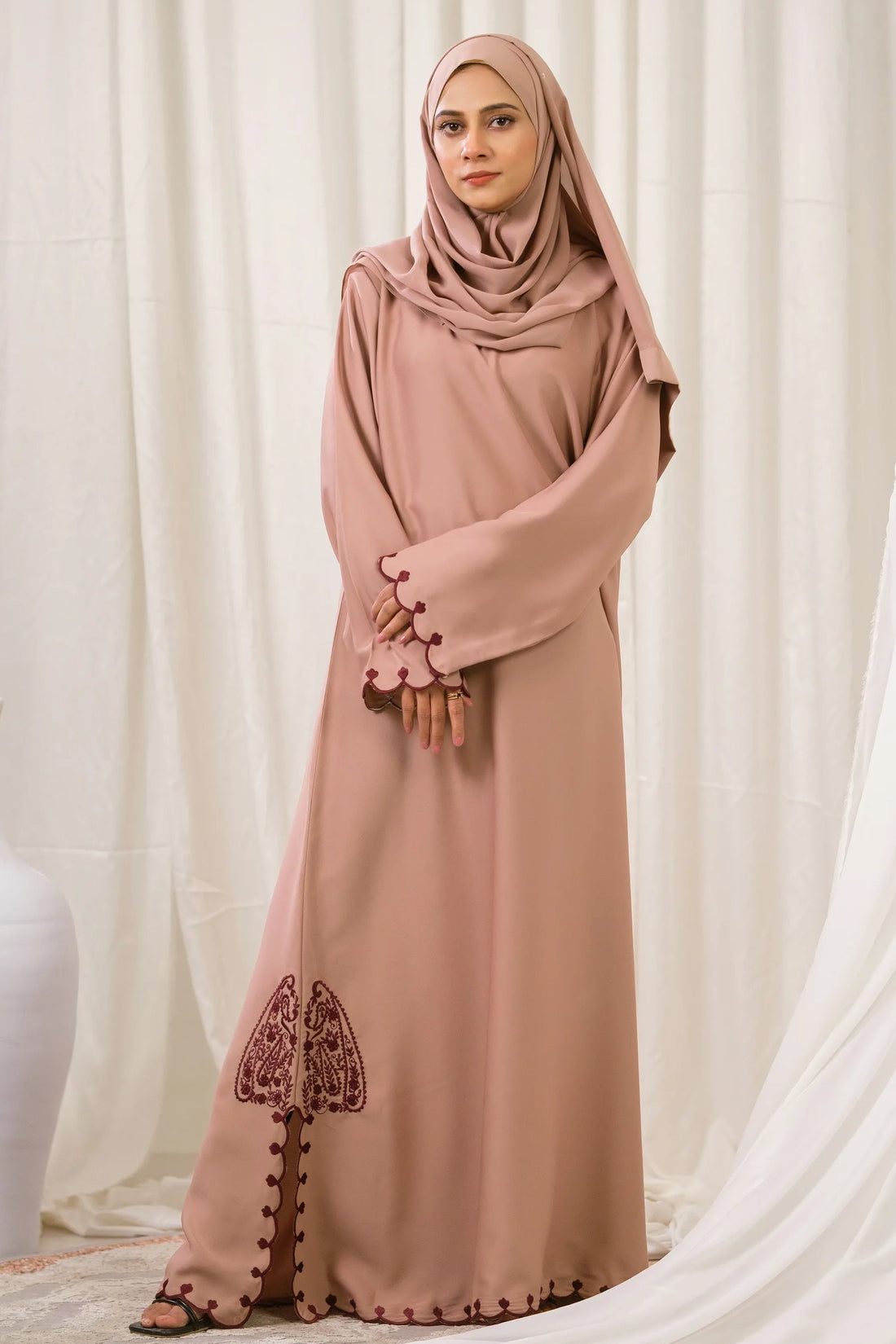 Dhaagey Petal Edge Front-Close Abaya in Nude Pink Nidha, showing asymmetrical maroon embroidery near the hem and scalloped trim.