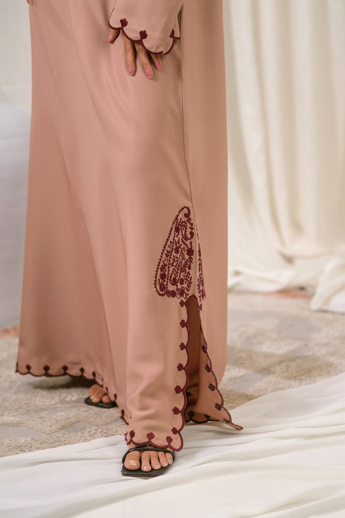 Dhaagey Petal Edge Front-Close Abaya in Nude Pink Nidha, showing asymmetrical maroon embroidery near the hem and scalloped trim.