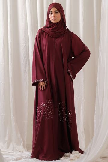 Dhaagey Ruby Vine Abaya in deep maroon Nidha, full length, showing luminous silver crystal stonework in a vine pattern on the hem and detailed stone-embellished cuffs.