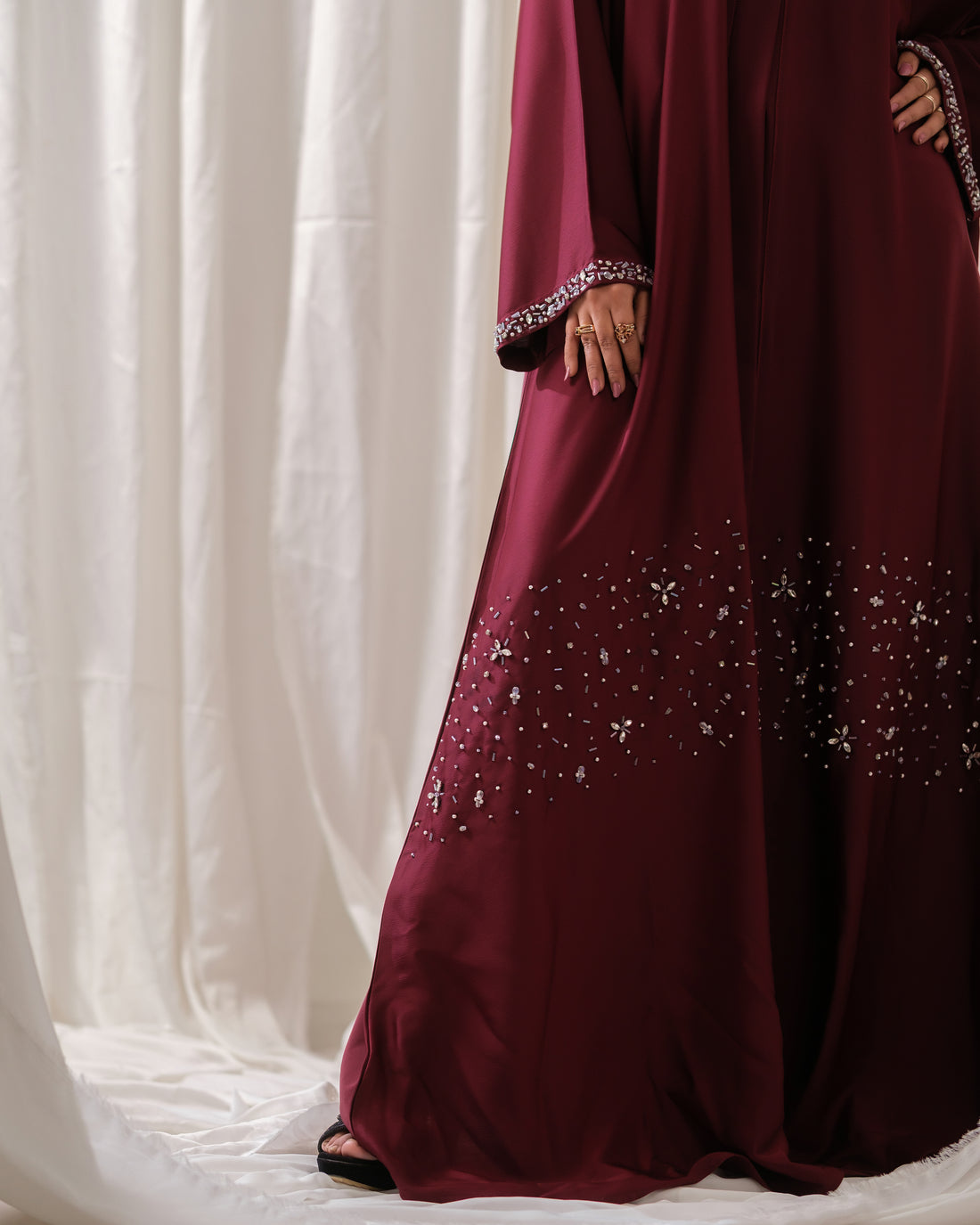 Dhaagey Ruby Vine Abaya in deep maroon Nidha, full length, showing luminous silver crystal stonework in a vine pattern on the hem and detailed stone-embellished cuffs.