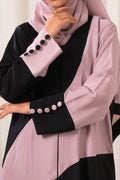 Dhaagey Intersect Abaya showing abstract curved color blocking in Black and Nude Pink with asymmetrical cuffs featuring contrasting color buttons. close up.