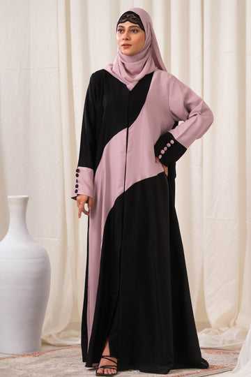 Dhaagey Intersect Abaya showing abstract curved color blocking in Black and Nude Pink with asymmetrical cuffs featuring contrasting color buttons.