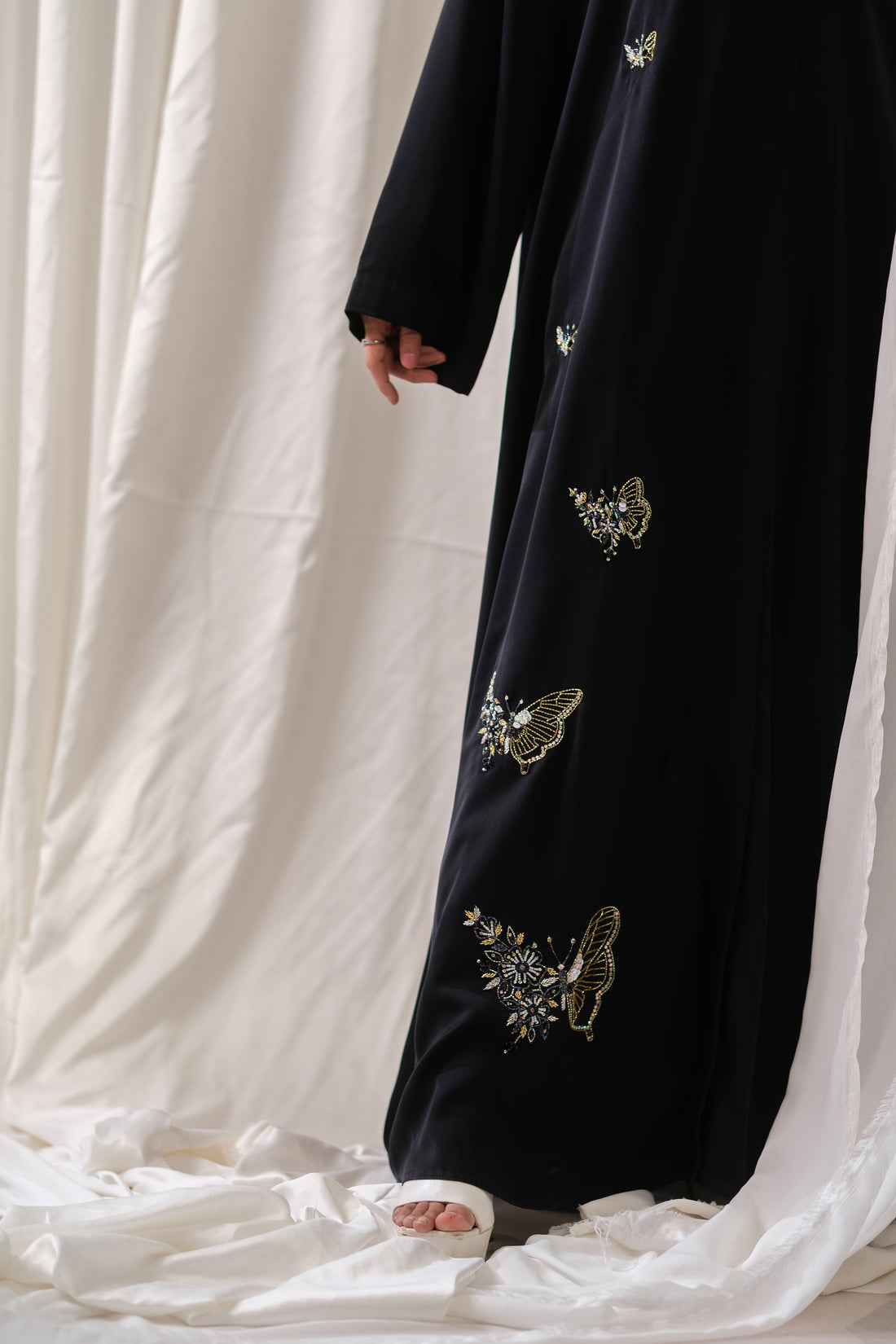 Dhaagey Monarch Front-Open Abaya in Black Nidha, showing vertical trail of beaded butterfly motifs down the front and up the length of one sleeve.