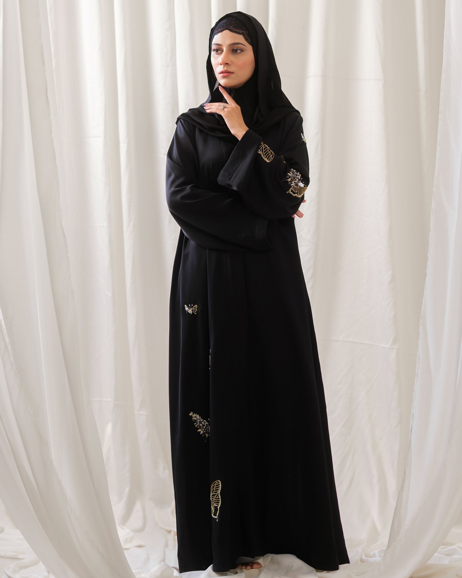 Dhaagey Monarch Front-Open Abaya in Black Nidha, showing vertical trail of beaded butterfly motifs down the front and up the length of one sleeve.